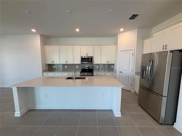 a kitchen with stainless steel appliances granite countertop a refrigerator a stove and a sink