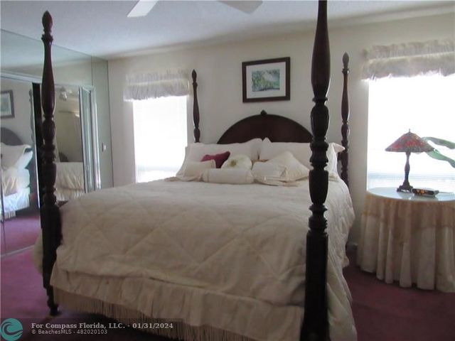 a bedroom with a bed wooden floor and a large window