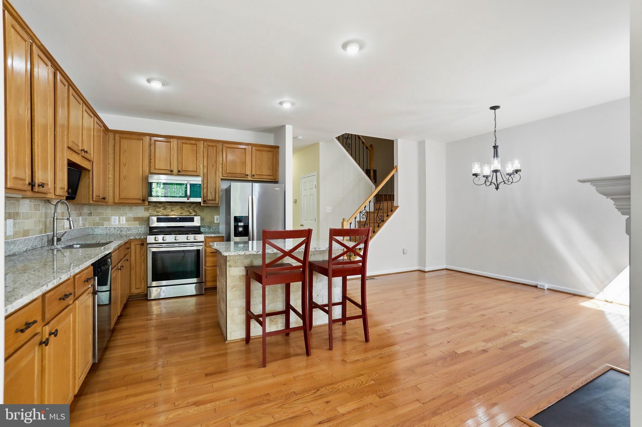 21648 Frame Square Broadlands, VA 20148 - Photo 11 of 36 a kitchen with stainless steel appliances kitchen island granite countertop a stove top oven a sink a dining table and chairs with wooden floor