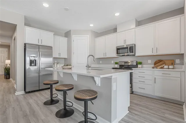 a kitchen with kitchen island granite countertop a sink cabinets and stainless steel appliances