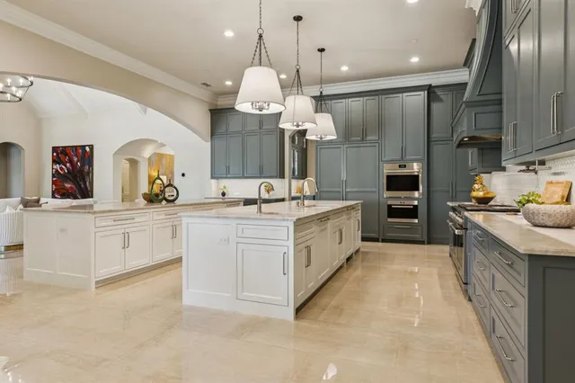 a large white kitchen with cabinets a sink and stainless steel appliances