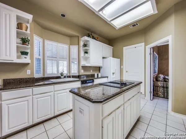 a kitchen with granite countertop a sink stainless steel appliances white cabinets and a window