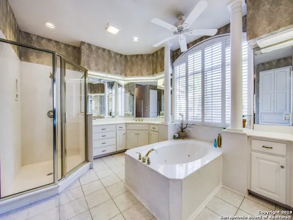 a bathroom with a tub a sink a mirror and a shower