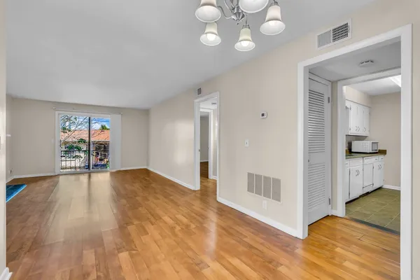 a view of empty room with wooden floor and fan
