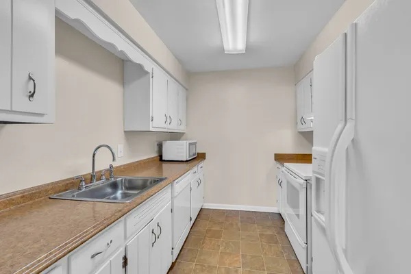 a kitchen with granite countertop white cabinets and white appliances