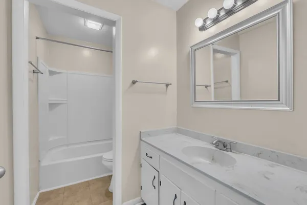 a bathroom with a granite countertop sink a mirror and a bathtub