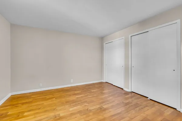 a view of an empty room with wooden floor and closet