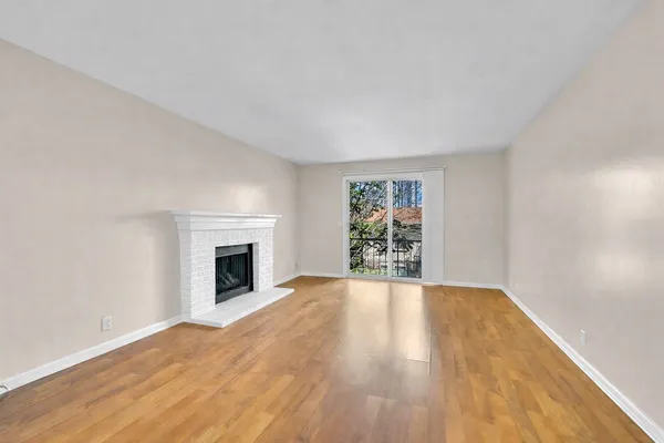 a view of empty room with wooden floor and fireplace