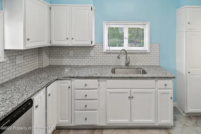 a kitchen with granite countertop white cabinets and sink