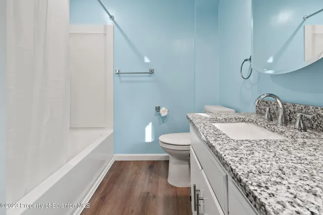 a bathroom with a granite countertop sink a toilet and shower