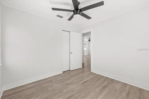 an empty room with wooden floor and a ceiling fan