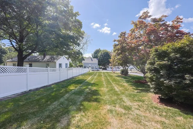 a view of a house with a yard and large trees