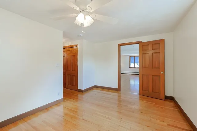 an empty room with wooden floor closet and windows