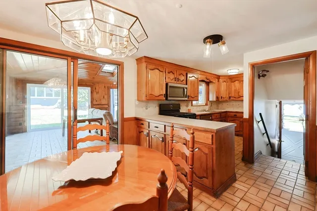 a open kitchen with stainless steel appliances granite countertop a refrigerator a stove top oven and a dining table with wooden floor