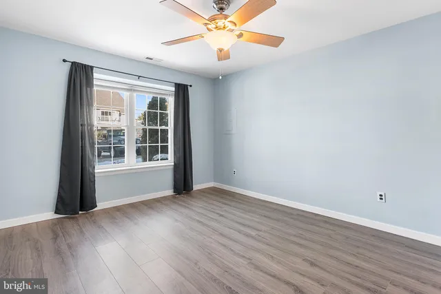 an empty room with wooden floor fan and windows