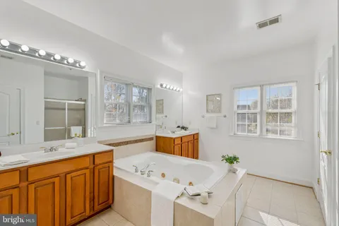 a spacious bathroom with double vanity a mirror a bathtub shower sink and mirror