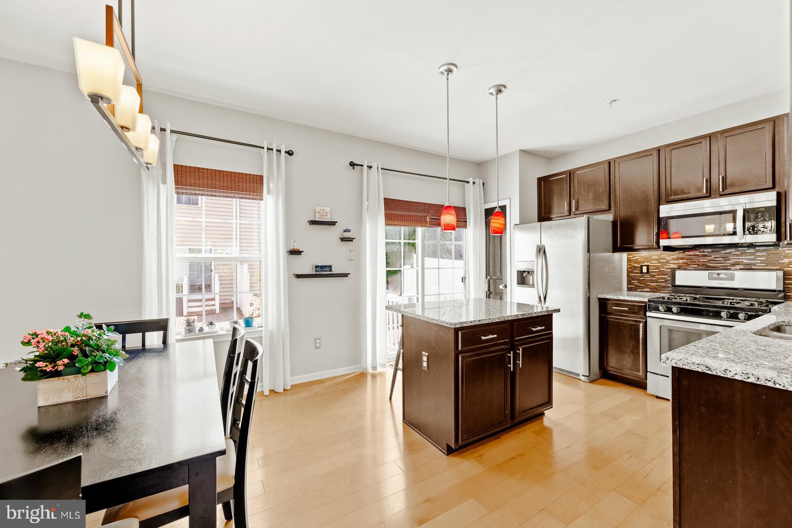 3669 Jacob Stout Road, Unit 8 Doylestown, PA 18902 - Photo 12 of 38 a kitchen with stainless steel appliances granite countertop a refrigerator a stove a sink dishwasher a dining table and chairs with wooden floor