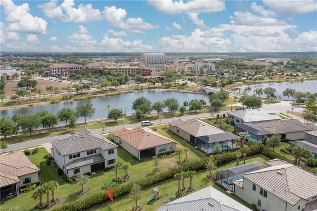 an aerial view of residential houses with outdoor space and lake view in back