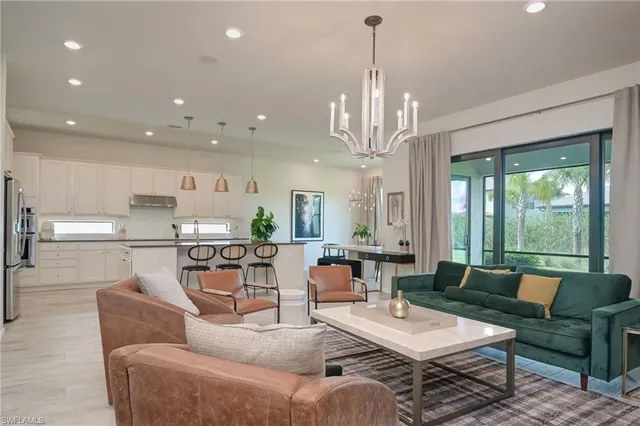 a living room with furniture dining table a large window and a chandelier