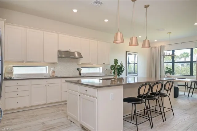 a kitchen with white cabinets and sink