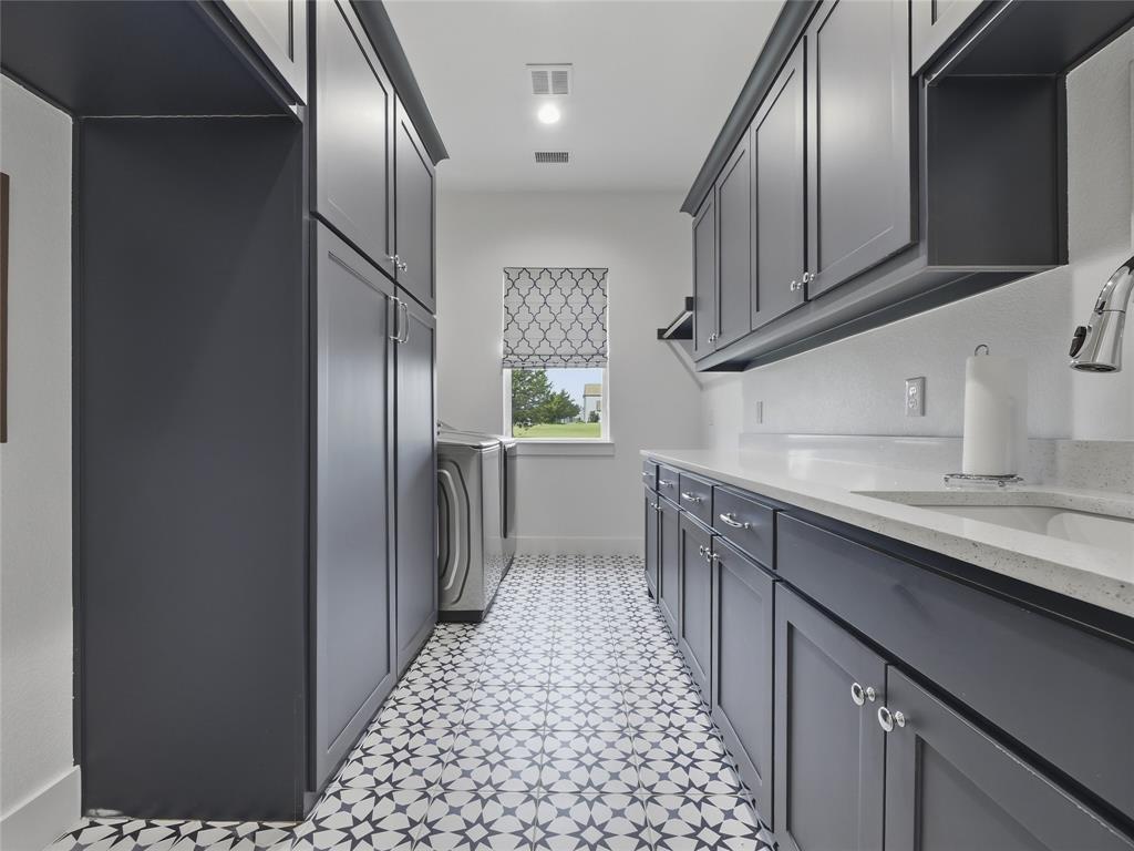 4211 Azalea Way Midlothian, TX 76065 - Photo 25 of 39 Laundry room featuring patterned tile flooring, extensive dark cabinetry with chrome hardware, white countertops, and a built-in sink with a gooseneck faucet