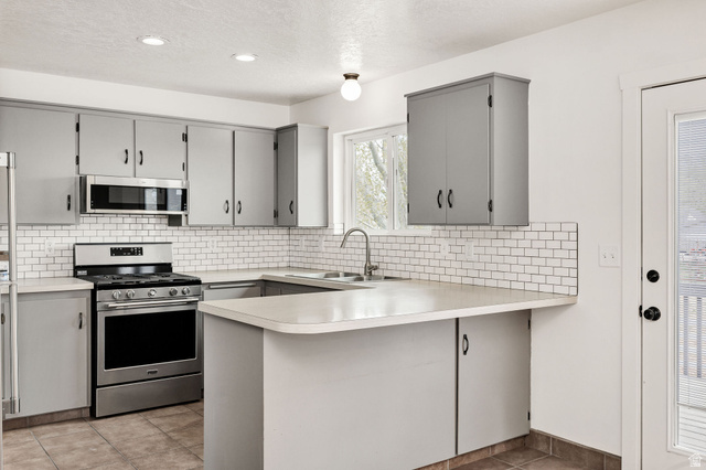 365 South Center Street Fielding, UT 84311 - Photo 13 of 41 Kitchen featuring gray cabinetry, a peninsula, stainless steel appliances, light countertops, and light tile patterned floors