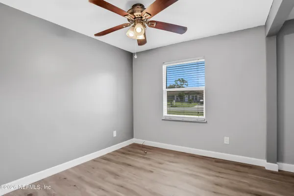 a view of an empty room with window and wooden floor