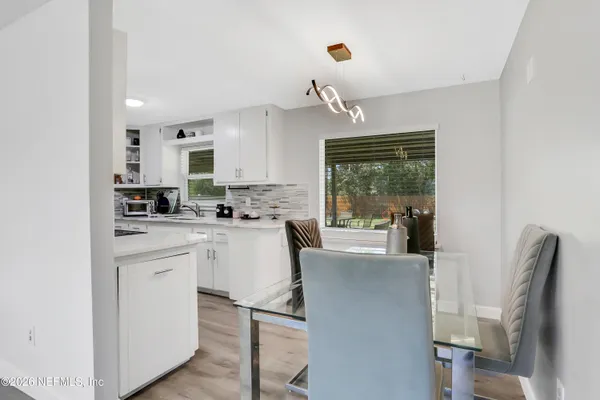 a kitchen with stainless steel appliances granite countertop a refrigerator a sink dishwasher a stove and a dining table with wooden floor