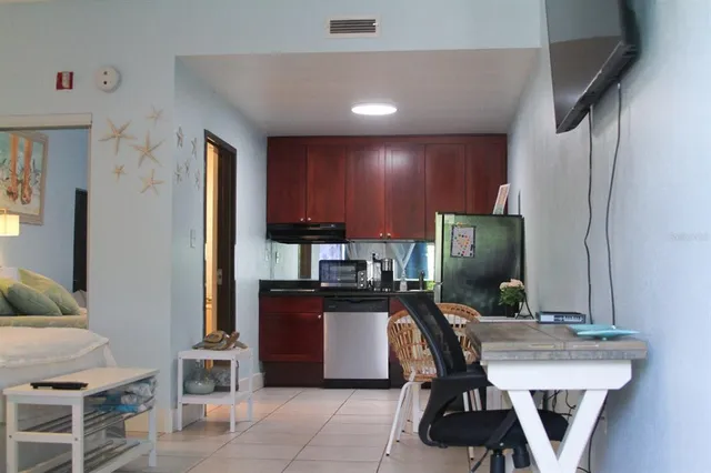 a kitchen with stainless steel appliances a dining table chairs and a refrigerator