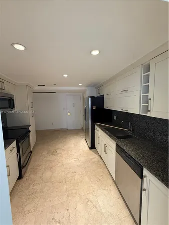 a kitchen with white cabinets and black appliances