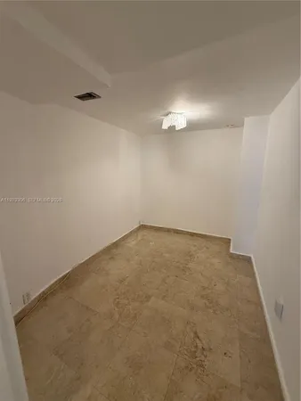 an empty room with a chandelier fan and windows