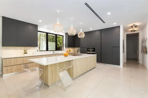 a large kitchen with a large counter top a sink stainless steel appliances and cabinets