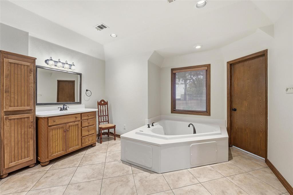 1607 North Main Street Euless, TX 76039 - Photo 29 of 40 a bathroom with a bathtub a sink a mirror and a shower