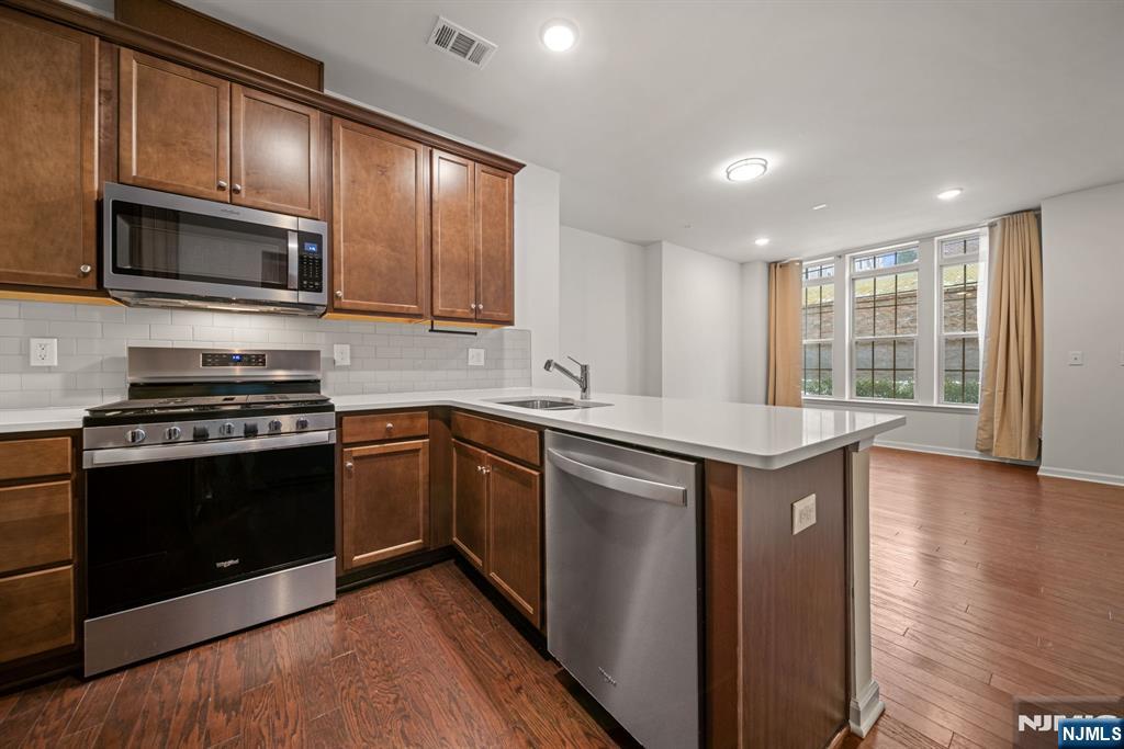 a kitchen with stainless steel appliances granite countertop a stove a microwave and a sink