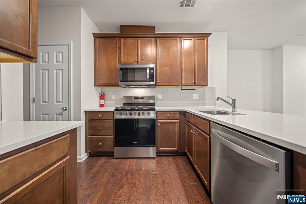 39 Arnold Drive Wood-Ridge, NJ 07075 - Photo 13 of 49 a kitchen with stainless steel appliances a sink cabinets and a stove top oven