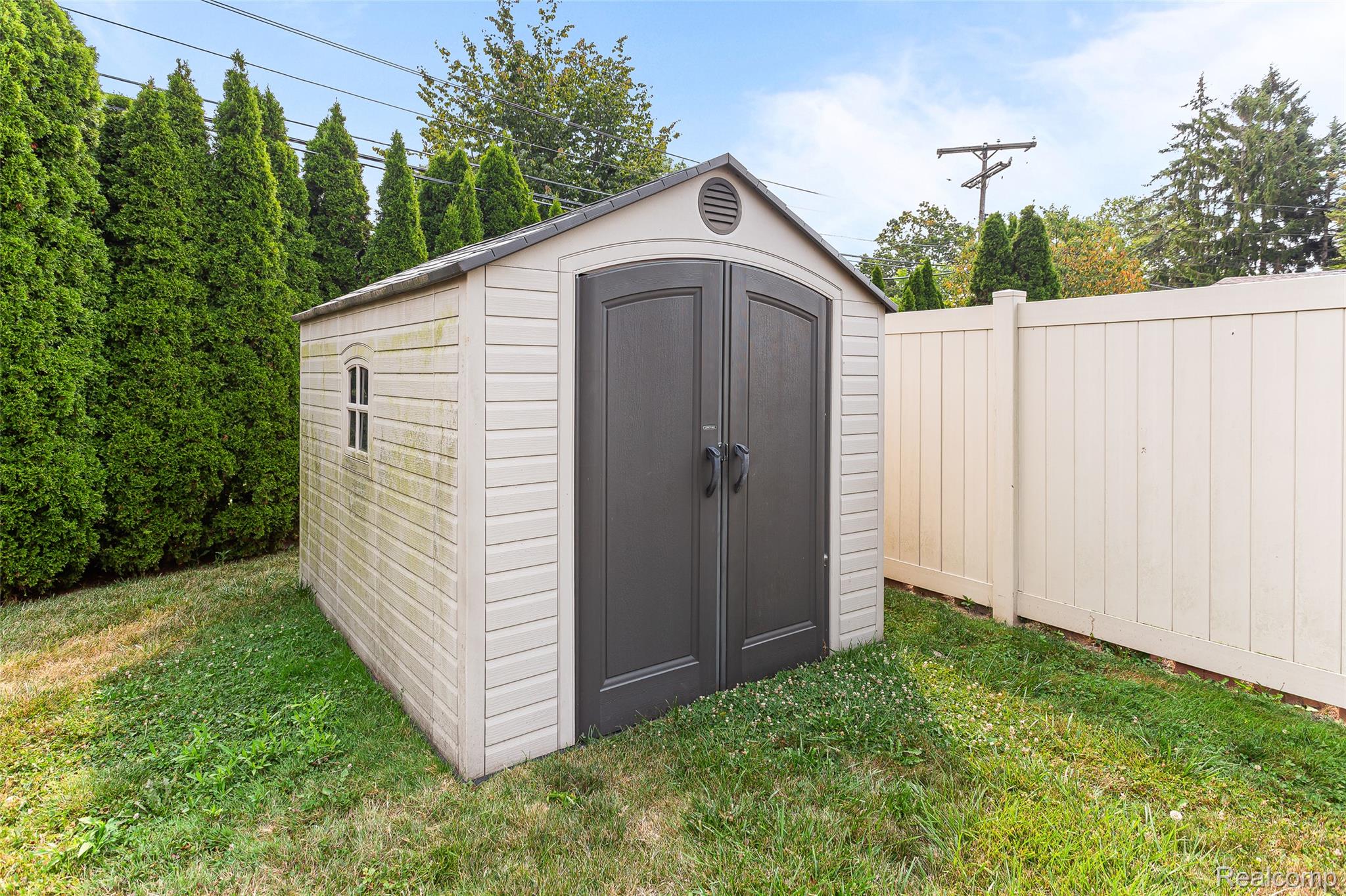 2345 Middlefield Road Trenton, MI 48183 - Photo 36 of 42 Outdoor storage shed featuring dual dark-paneled doors, a side window detail, and a roof vent