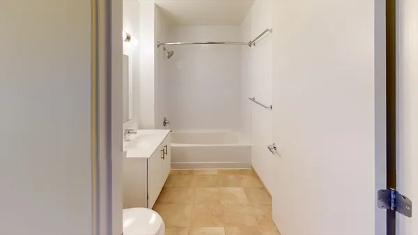 a bathroom with a tub shower sink and mirror