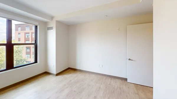 an empty room with wooden floor and windows