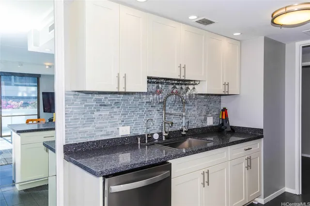 a kitchen with stainless steel appliances granite countertop a sink a stove and a white cabinets