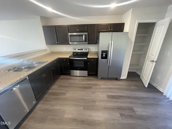 a kitchen with stainless steel appliances granite countertop a refrigerator a stove a sink and a microwave