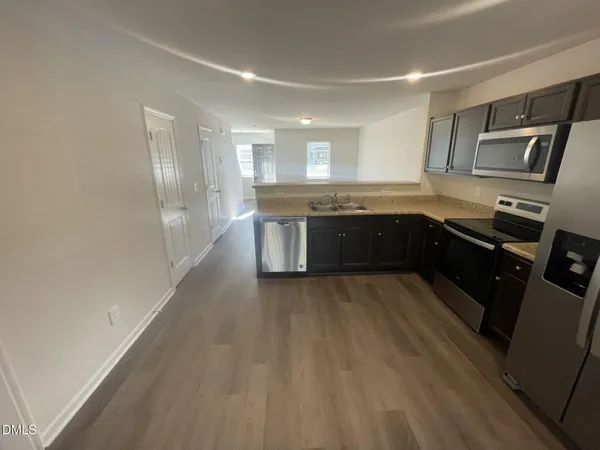 a large kitchen with wooden floor and stainless steel appliances