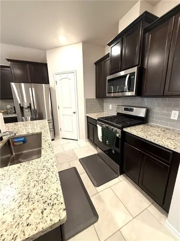 a kitchen with stainless steel appliances granite countertop a stove refrigerator and sink
