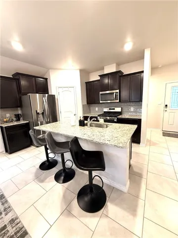 a living room with stainless steel appliances kitchen island granite countertop a sink and a stove top oven