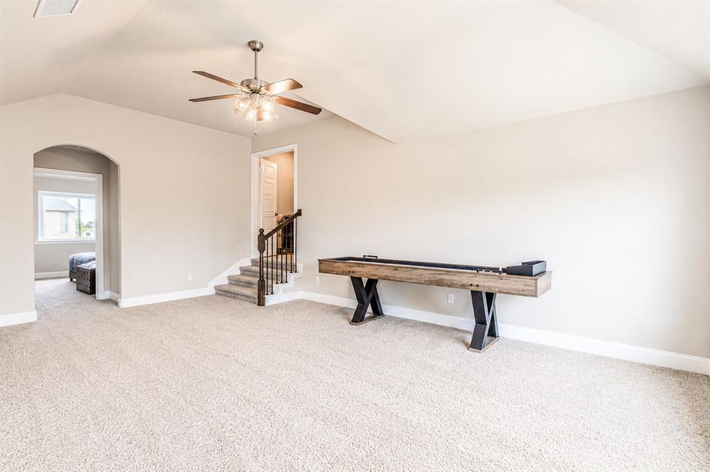 25 Morrison Road Howe, TX 75459 - Photo 17 of 27 Carpeted bonus room featuring a ceiling fan with light fixture, an arched doorway, and a carpeted staircase with wood handrail and black balusters