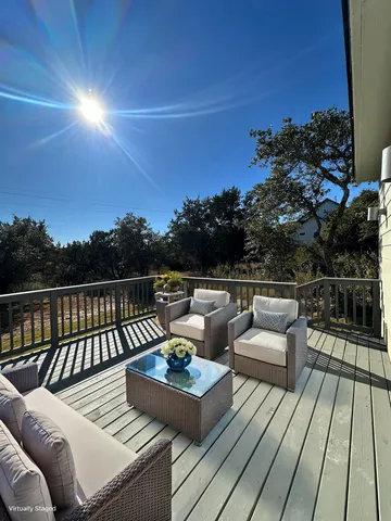 a view of deck with seating area and trees in the background
