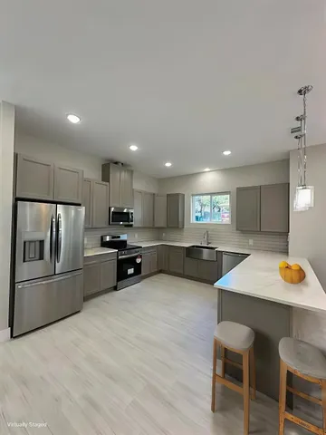 a kitchen with stainless steel appliances kitchen island granite countertop a refrigerator and a stove top oven with wooden floor