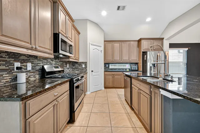 a kitchen with stainless steel appliances granite countertop a stove top oven a sink dishwasher a refrigerator and cabinets with wooden floor