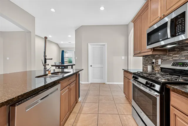a kitchen with stainless steel appliances granite countertop a stove a sink and a microwave