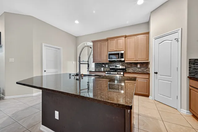 a kitchen with stainless steel appliances granite countertop a sink a stove and a refrigerator