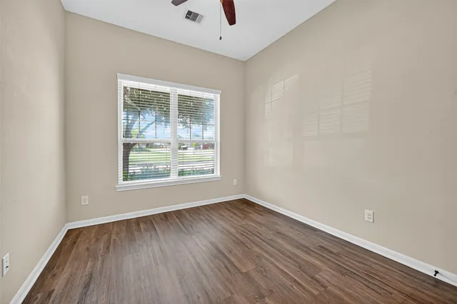 an empty room with wooden floor and windows